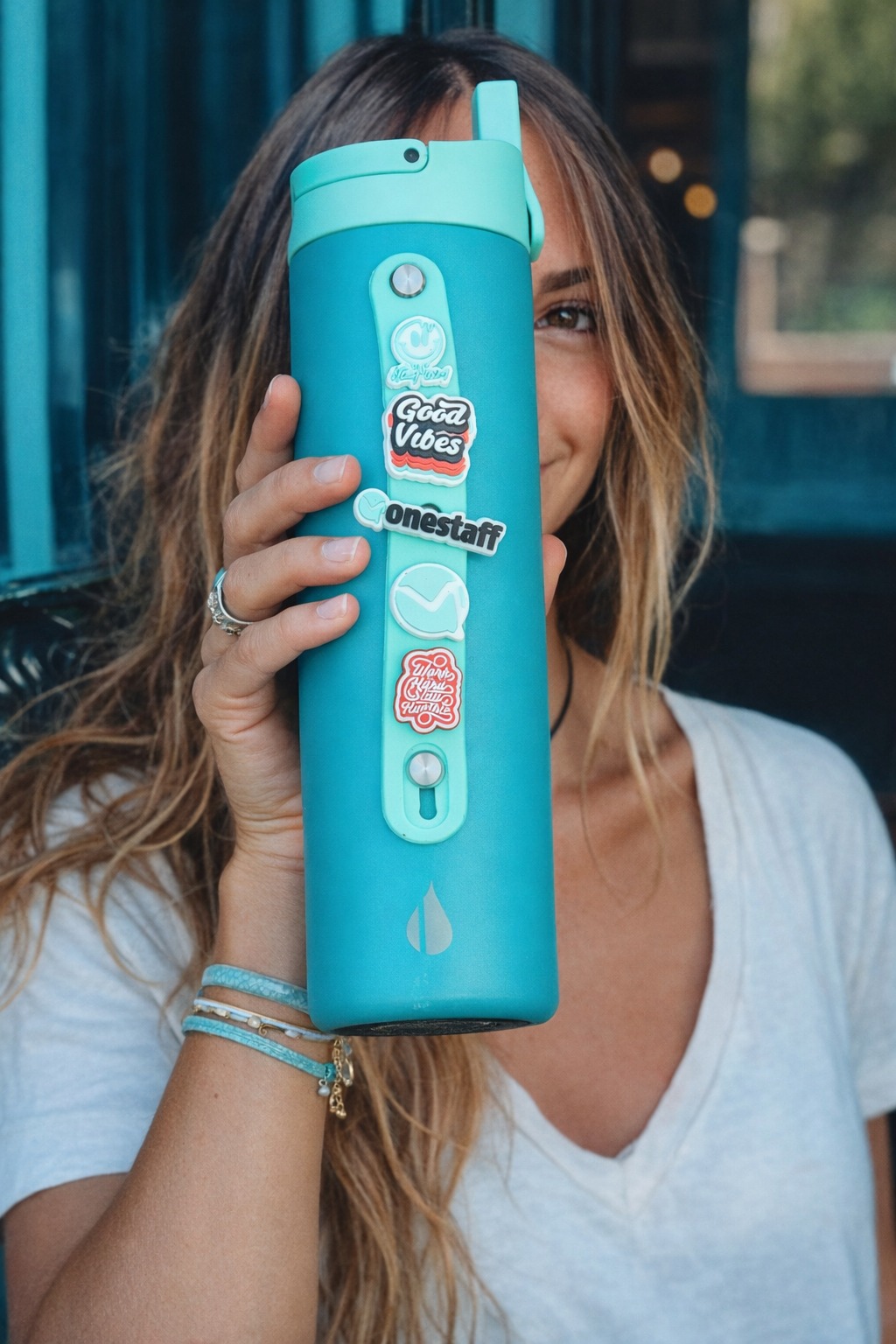 OneStaff-branded teal water bottle decorated with custom sticker pack — held by a travel nurse