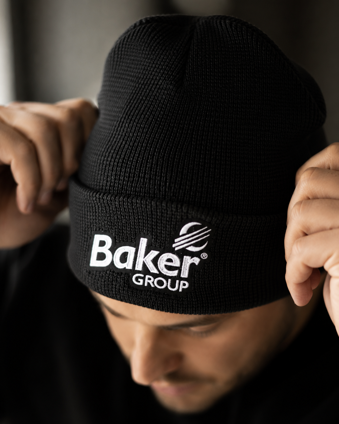 Embroidered Baker Group black beanie worn by a crew member