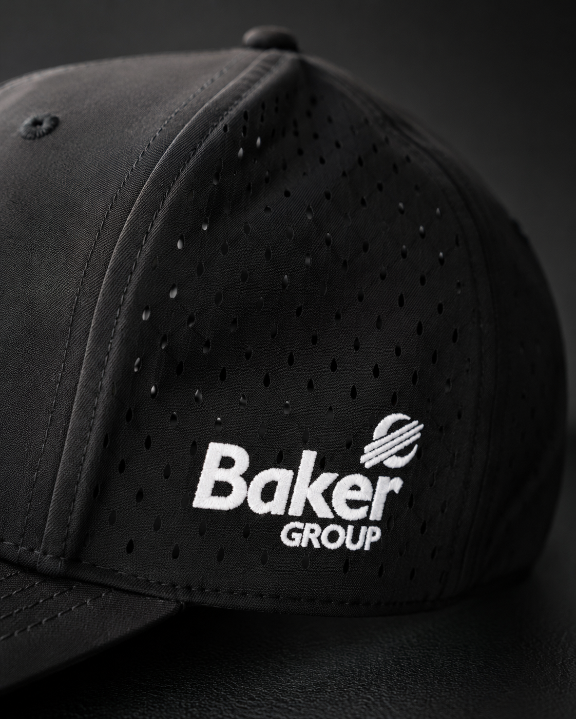 Macro detail of an embroidered Baker Group logo on a perforated performance cap