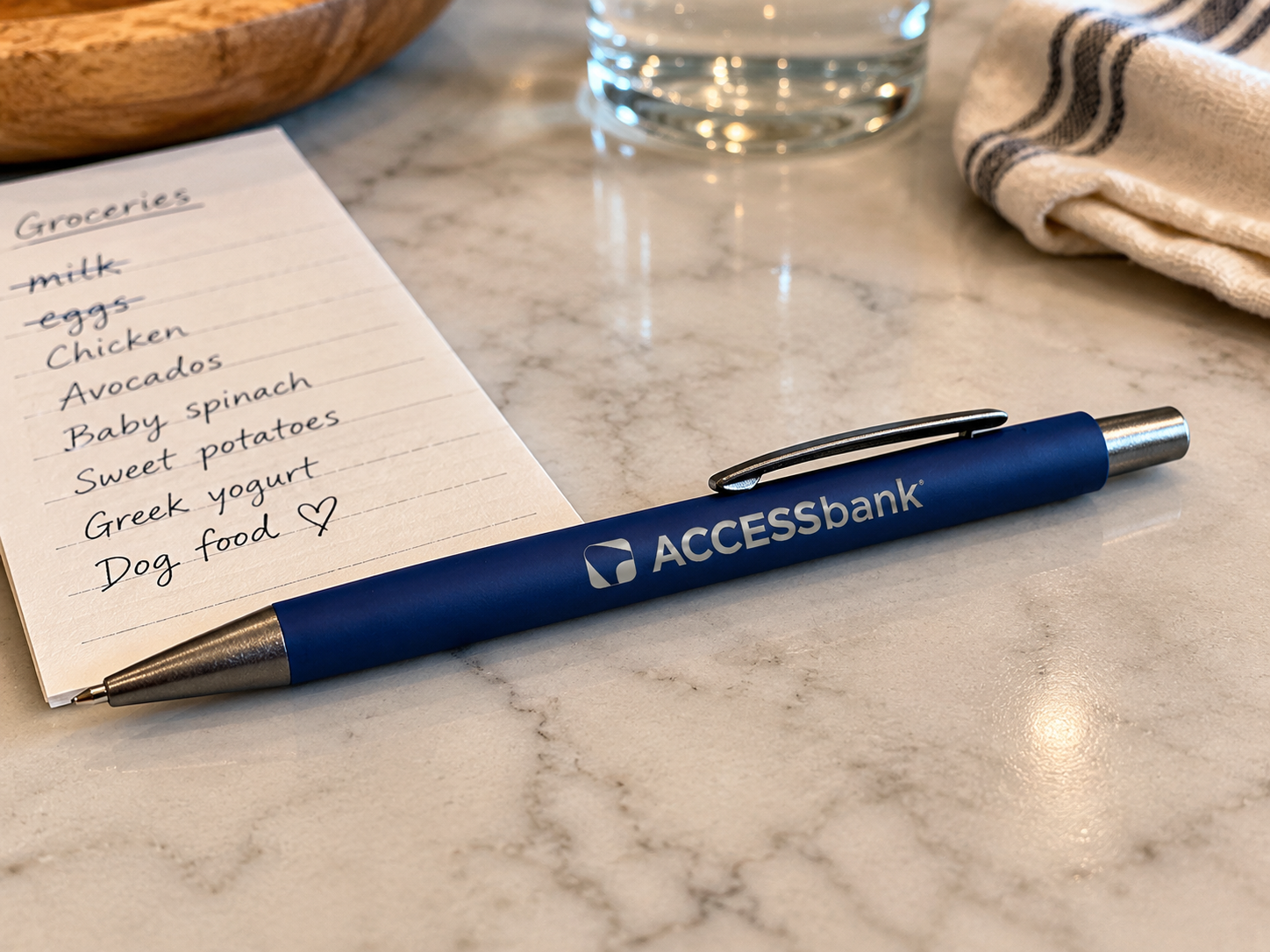 ACCESSbank branded pen on a marble countertop beside a handwritten grocery list