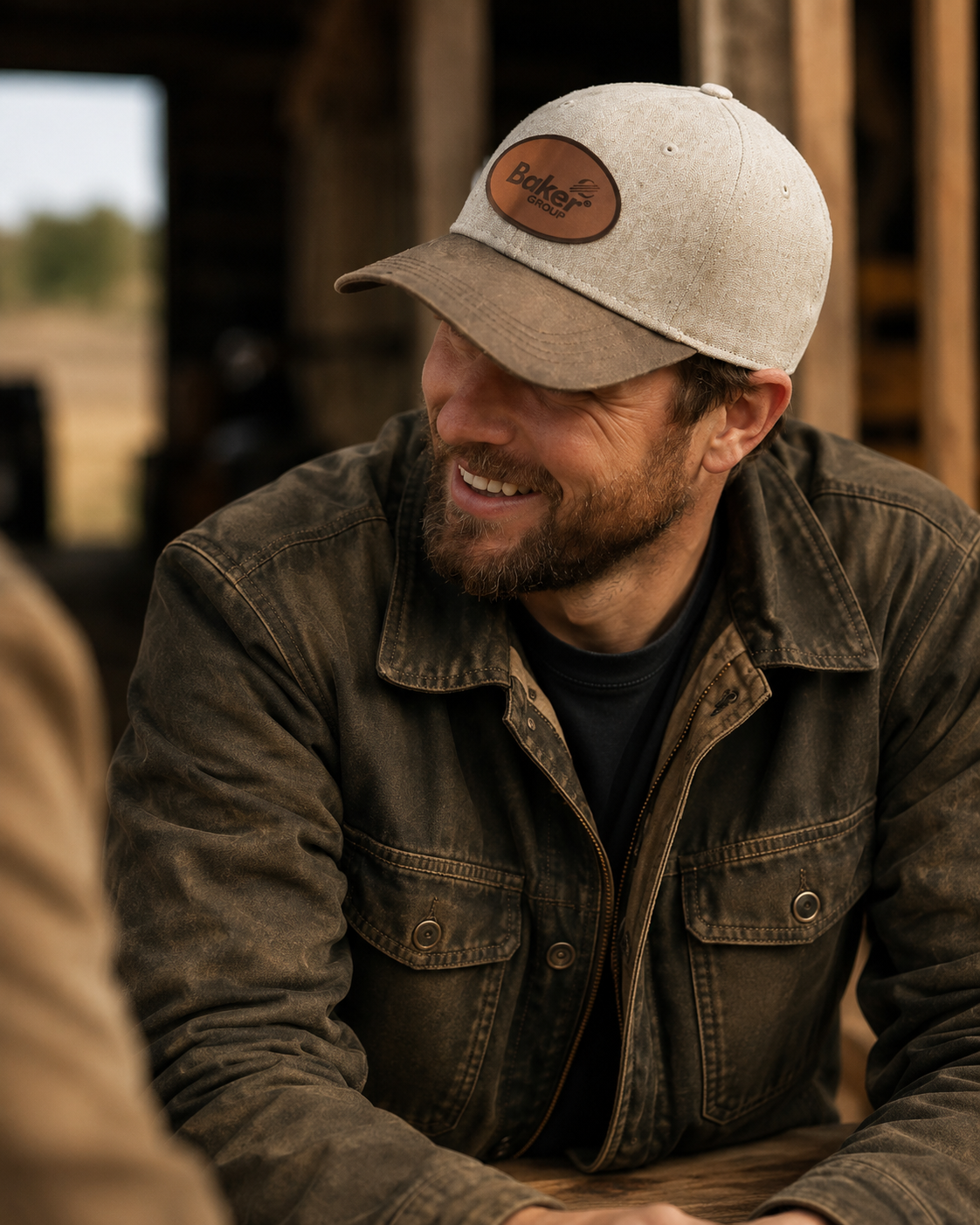 Baker Group leather-patch cap and field jacket worn at a barn meeting