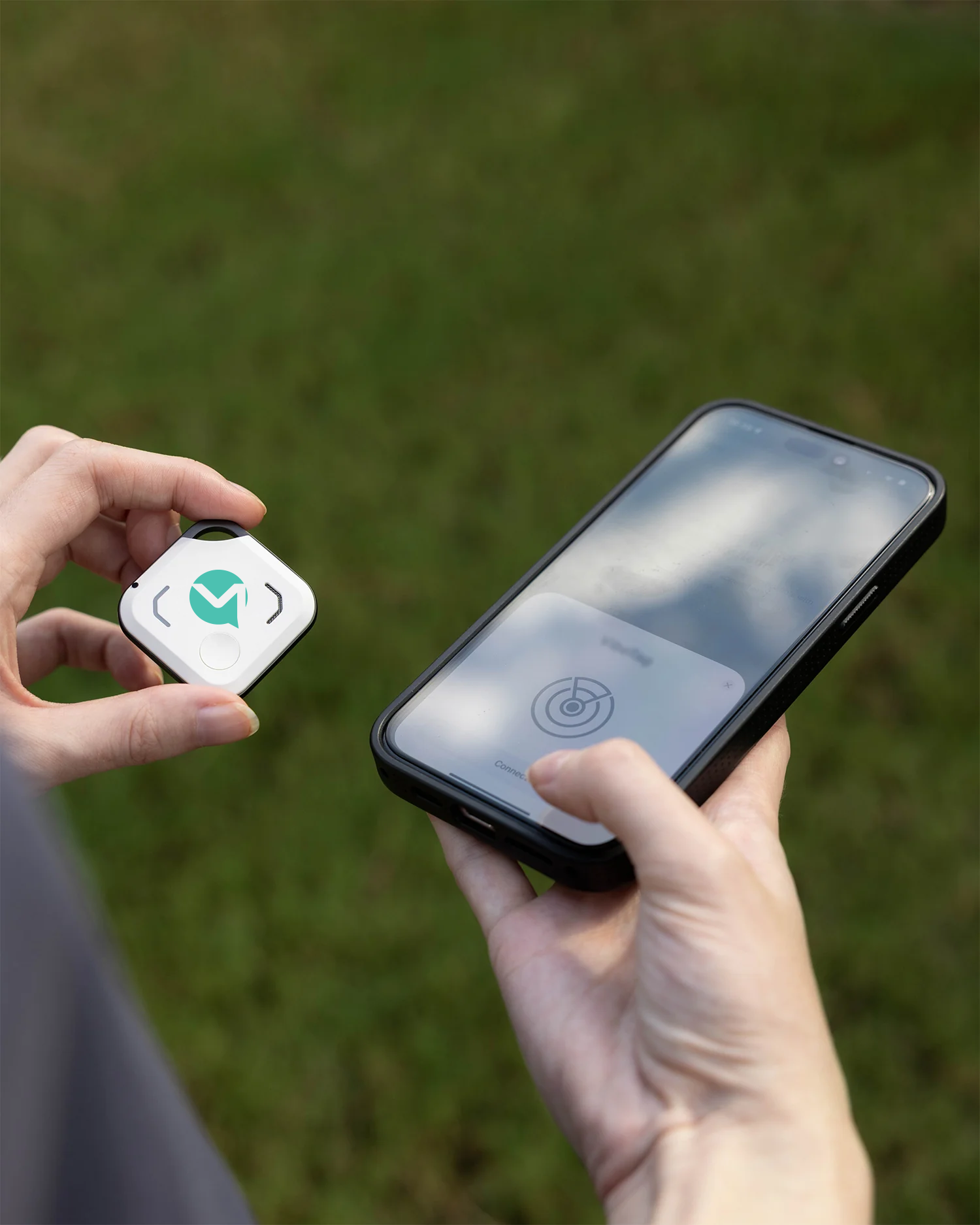 OneStaff Bluetooth tracker held next to a phone in pairing mode